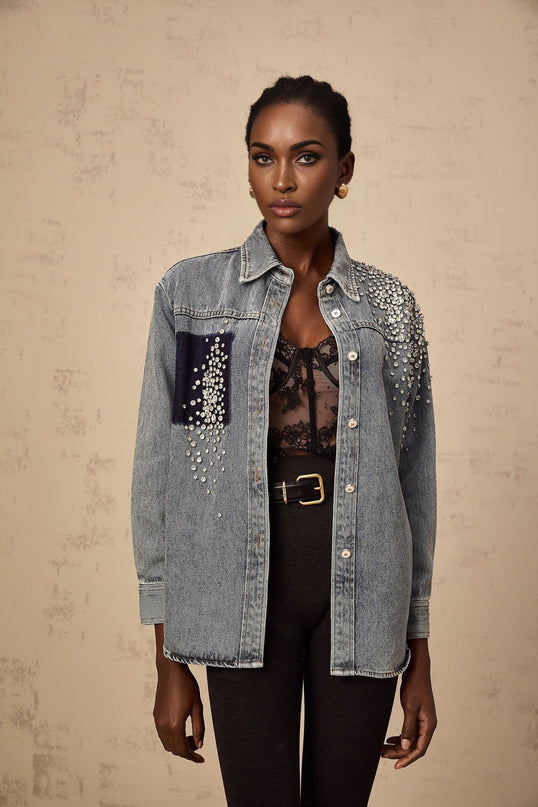 A light blue denim shirt with sparkling rhinestone embellishments featuring a classic collar and button front closure