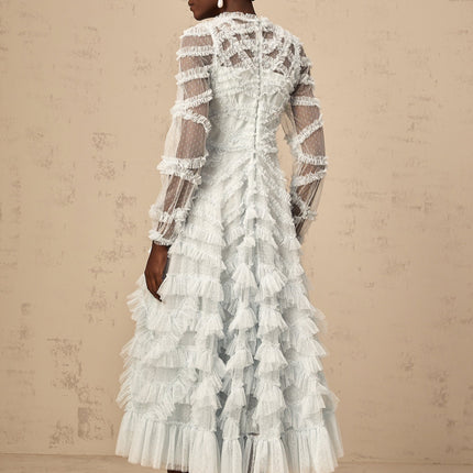 A light blue midi dress with small white polka dots featuring ruffled details and a feminine silhouette