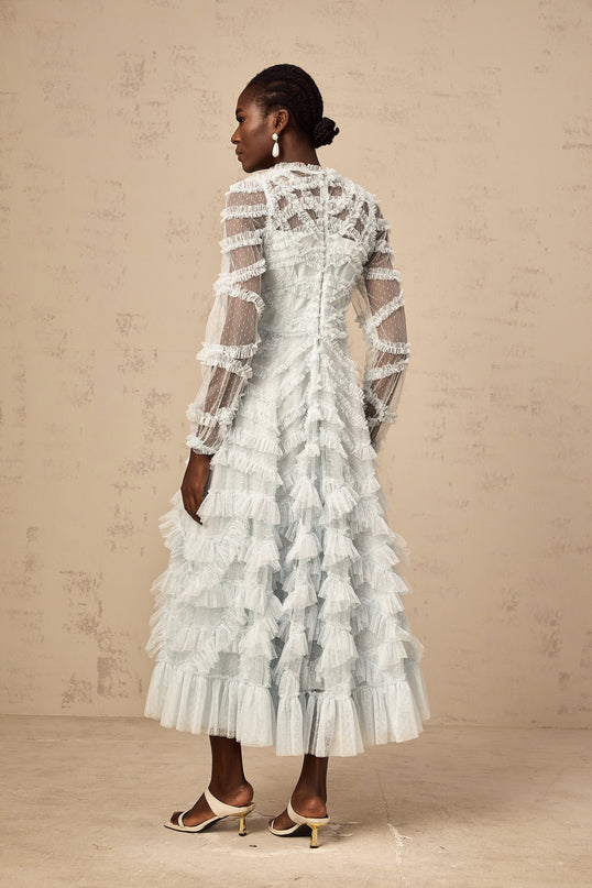 A light blue midi dress with small white polka dots featuring ruffled details and a feminine silhouette