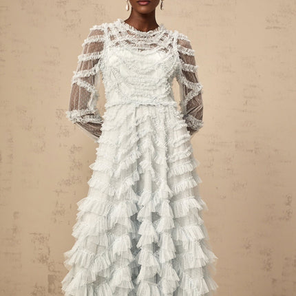 A light blue midi dress with small white polka dots featuring ruffled details and a flowy silhouette