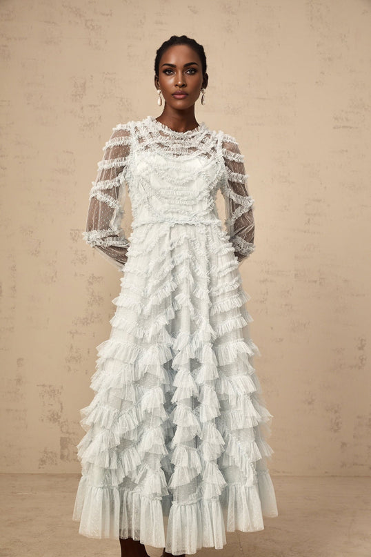 A light blue midi dress with small white polka dots featuring ruffled details and a flowy silhouette