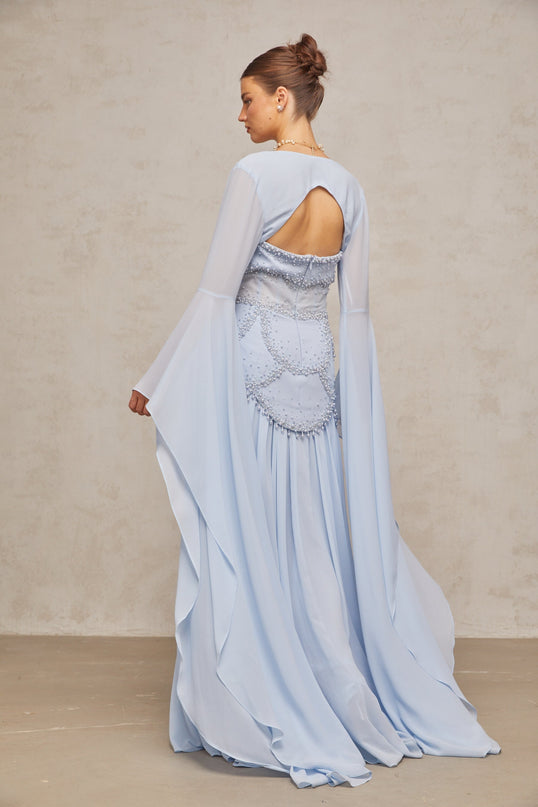 A light blue pleated maxi dress with faux pearl embellishments styled on a mannequin or model against a plain background