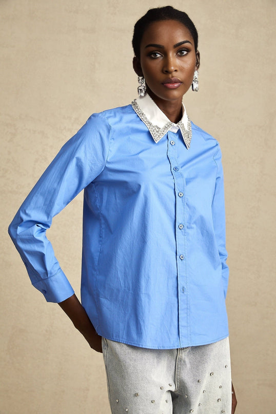 A light blue shirt with a color block design featuring darker blue sections and rhinestone embellishments