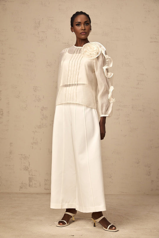 A light colored blouse with delicate three dimensional flower details on sheer fabric