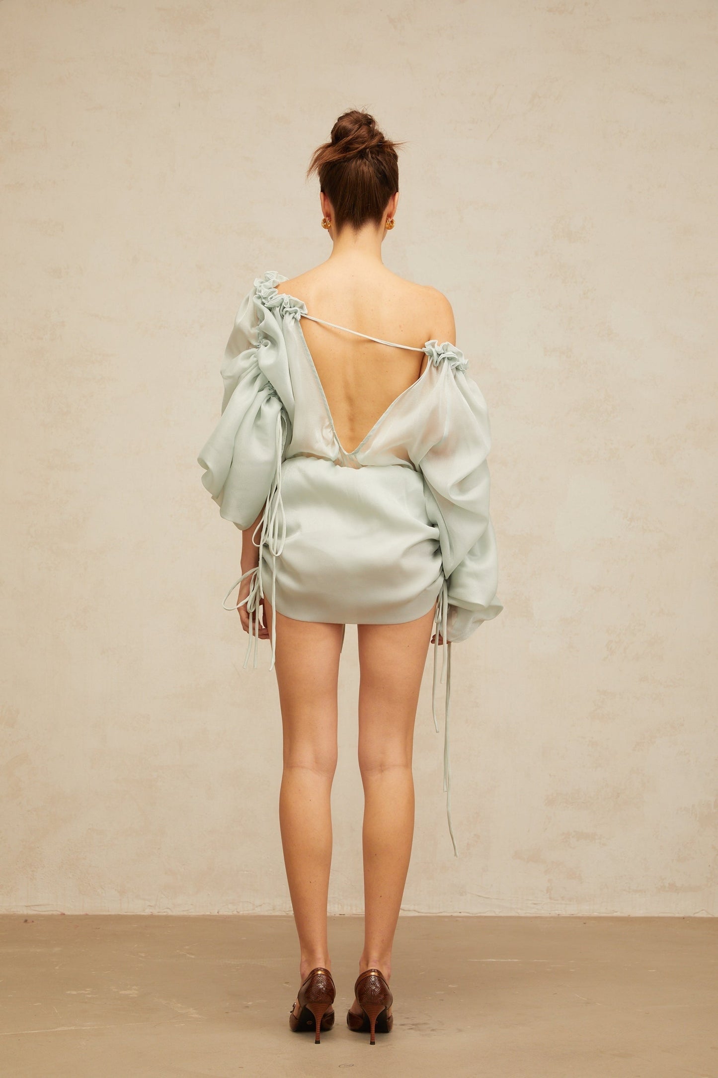 A light green mini dress with ruched fabric and ruffled trim details named Beryl