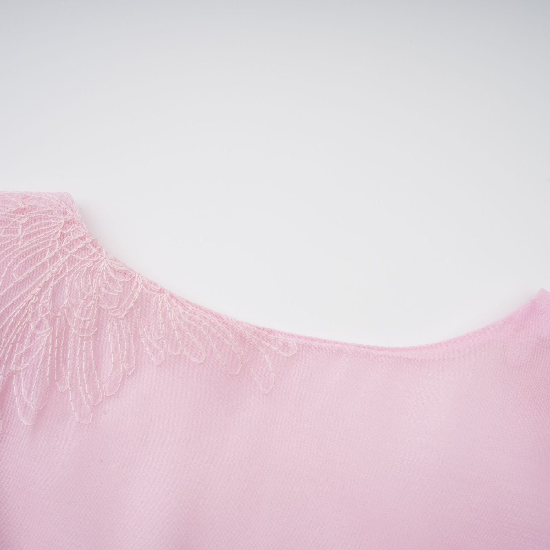 A light pink mini dress with floral embroidery and a layered skirt design