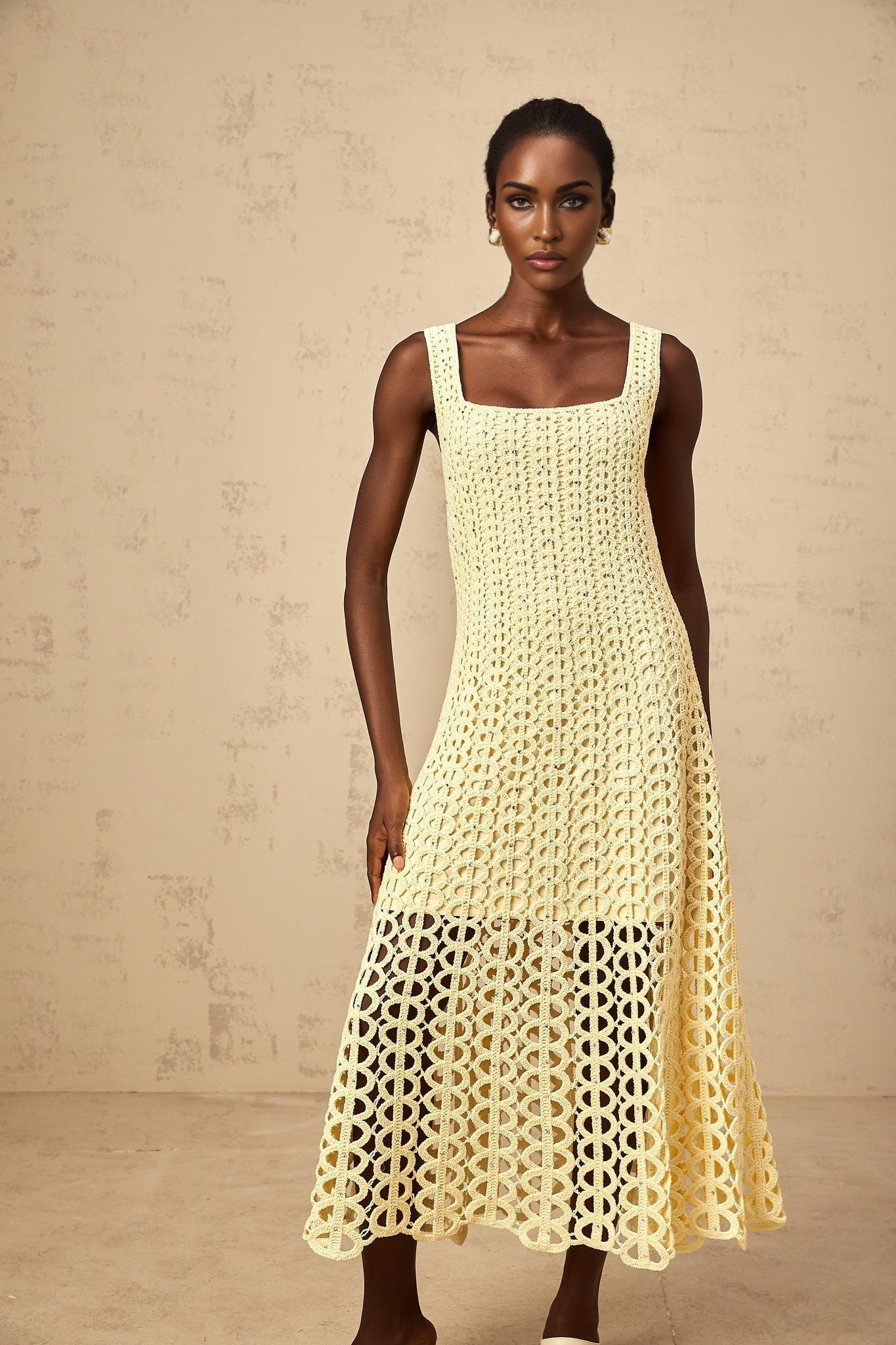 A light yellow midi dress with crochet knit pattern featuring embellishments and cut out details