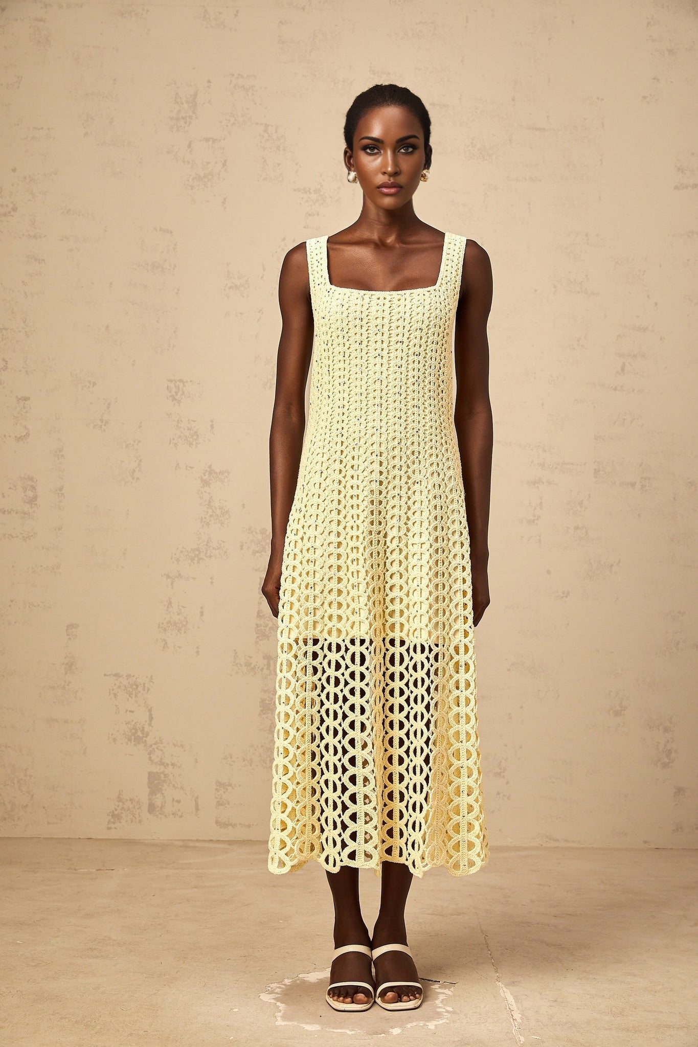 A light yellow midi dress with embellishments and cut out details featuring a crochet knit pattern