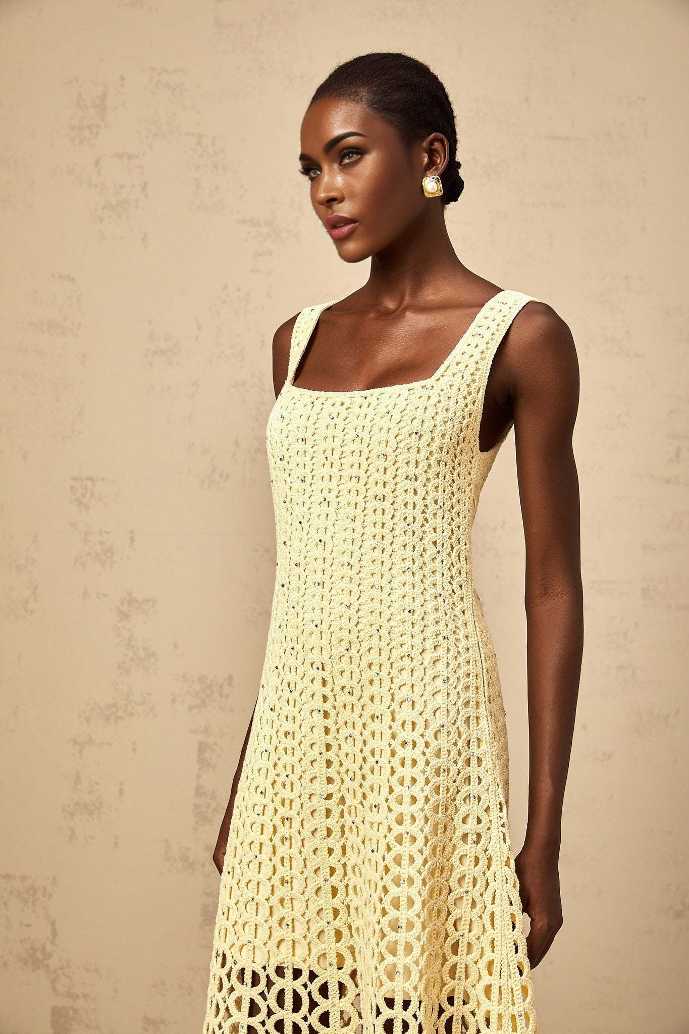 A light yellow midi dress with embellishments and cutout details featuring a crochet knit pattern