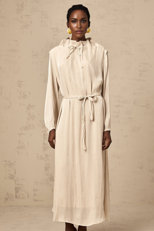 A lightcolored tulle midi dress with a selftie waist and flowy skirt worn by a model against a plain background
