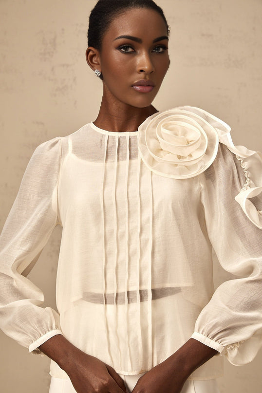 A lightweight cream colored blouse with delicate three dimensional floral appliques scattered across the semi transparent fabric