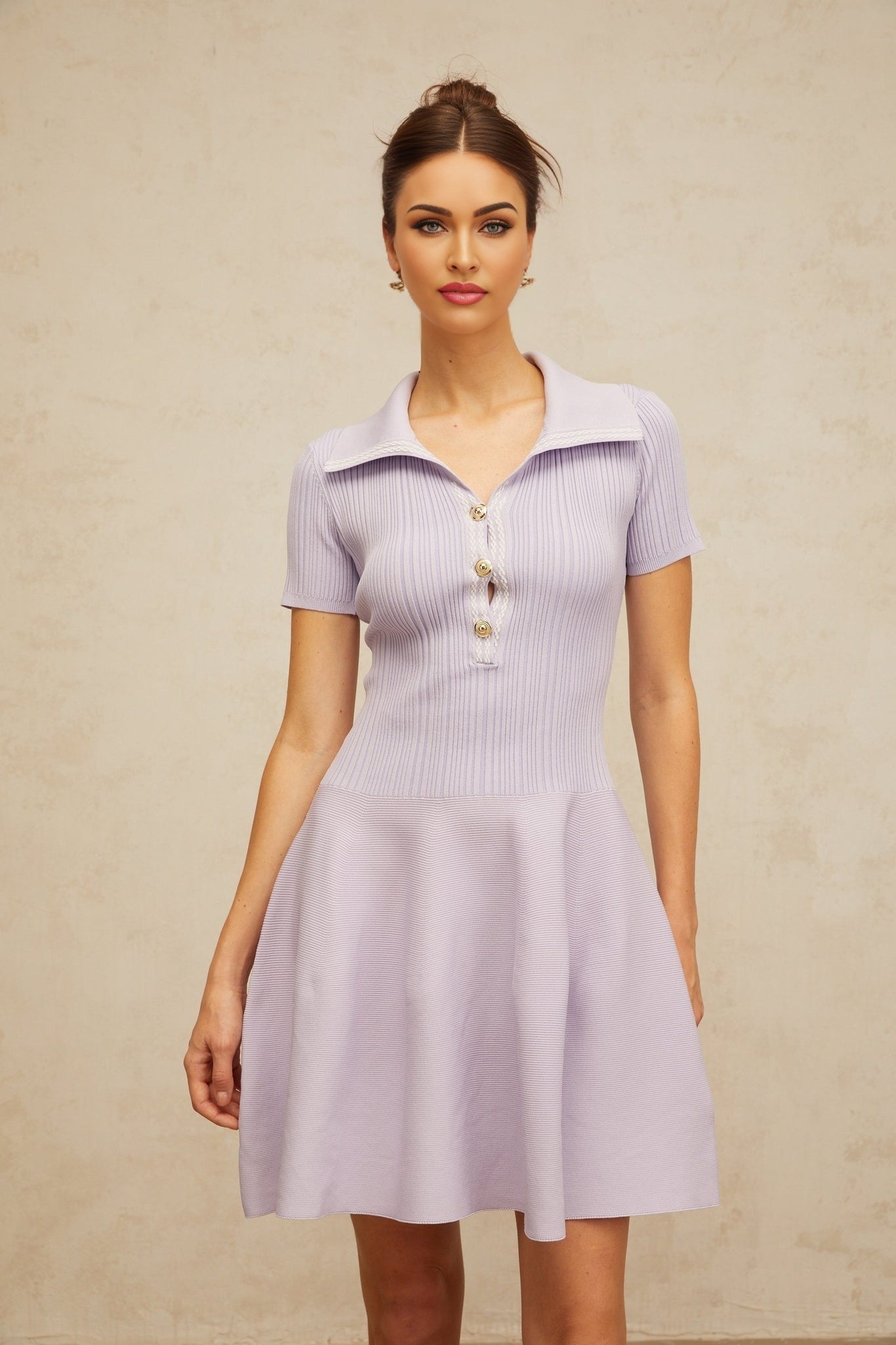 A lilac colored mini dress with a flared skirt and shirred bodice made from knit fabric The dress has a short length and is named Vanessa