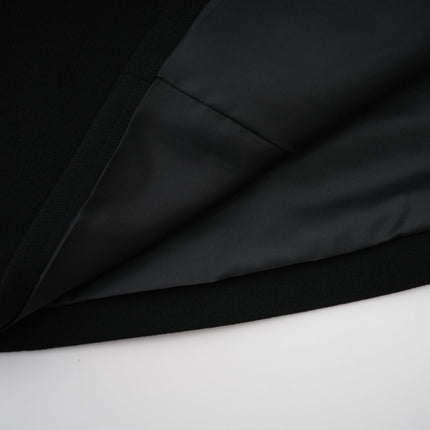 A long black maxi dress with a blazer style top featuring embellishments worn by a model against a plain background