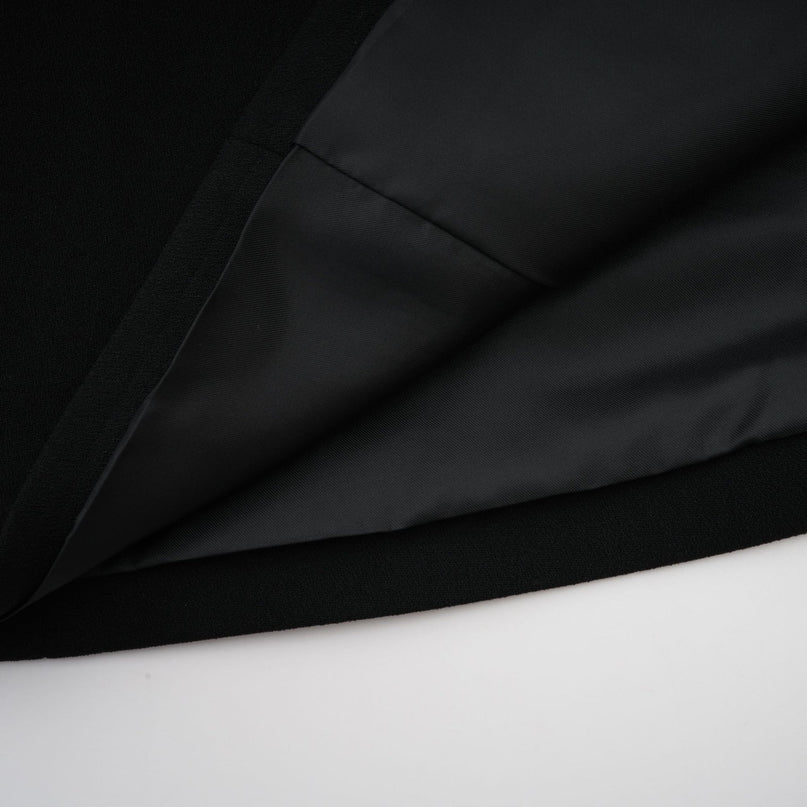 A long black maxi dress with a blazer style top featuring embellishments worn by a model against a plain background