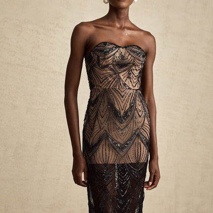 A long black maxi dress with a corset bodice covered in shimmering sequins and a flowing sheer mesh skirt