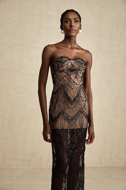 A long black maxi dress with a corset bodice covered in shimmering sequins and a flowing sheer mesh skirt
