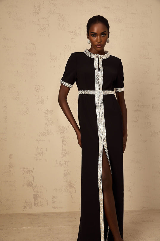 A long black maxi dress with a front slit and crystal embellishments worn by a model