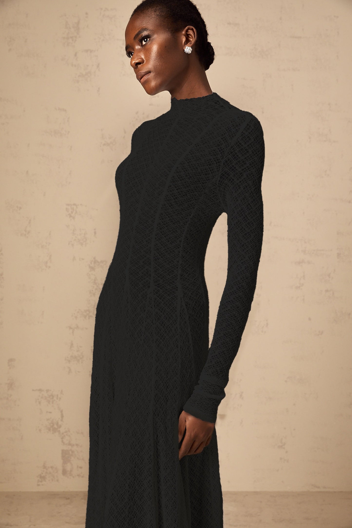 A long black maxi dress with a wavy lace pattern covering the entire garment called the Athena dress