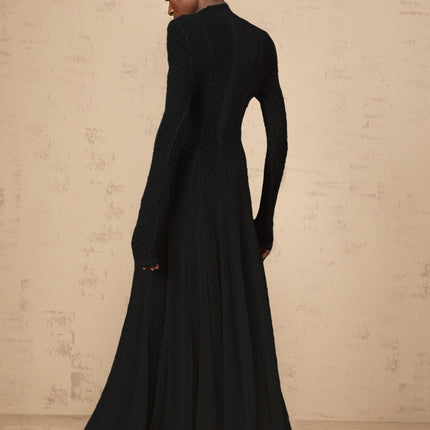 A long black maxi dress with a wavy lace pattern covering the entire garment The dress features a fitted bodice and flows into a fulllength skirt