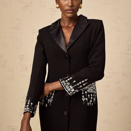 A long black maxi dress with blazer style top embellished with decorative details and featuring a feminine silhouette