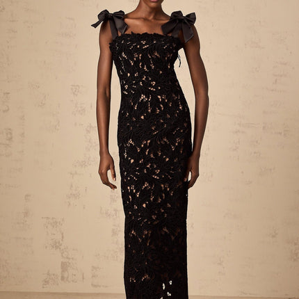 A long black maxi dress with delicate floral embroidery details worn by a model standing against a plain background