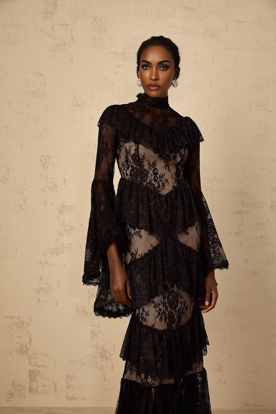 A long black maxi dress with floral lace pattern and ruffled details featuring a feminine silhouette