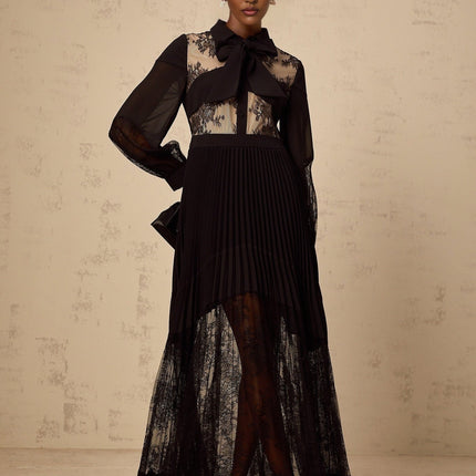 A long black maxi dress with pleated skirt and floral lace panels featuring a fitted bodice and flowing silhouette