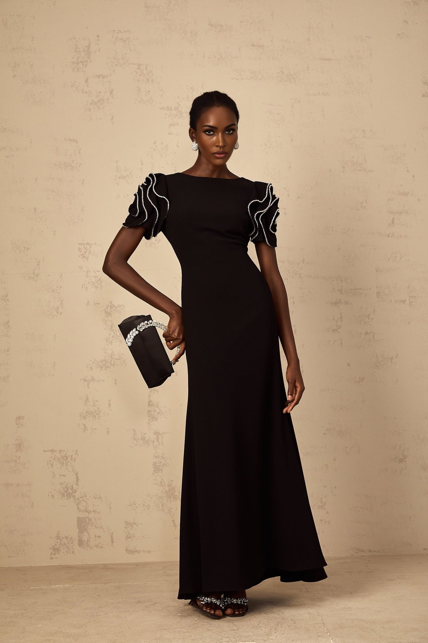 A long black maxi dress with ruffled details and embellishments designed by Bruyère featuring a flowing silhouette and elegant style