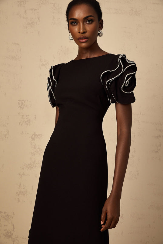 A long black maxi dress with ruffled details and embellishments designed by Bruyere featuring a flowing silhouette and elegant style