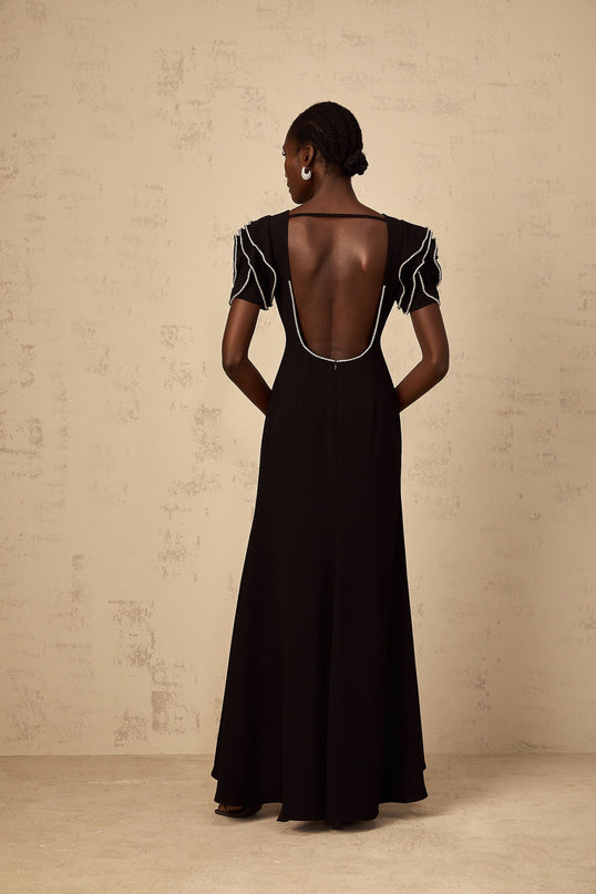 A long black maxi dress with ruffled details and embellishments featuring a flowing silhouette and elegant design by Bruyere