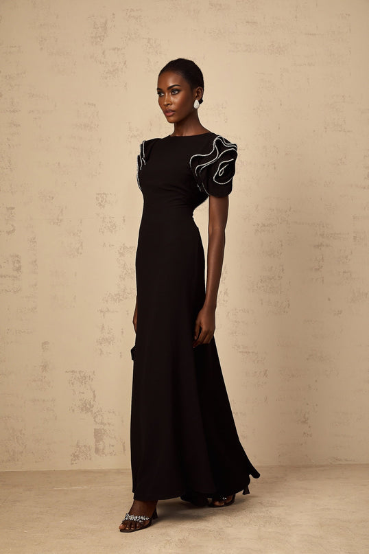 A long black maxi dress with ruffled details and embellishments from Bruyere featuring a flowing silhouette and elegant design