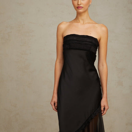 A long black satin maxi dress with sheer tulle panels and a fitted silhouette