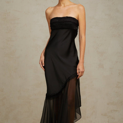 A long black satin maxi dress with sheer tulle panels featuring a fitted bodice and flowing skirt