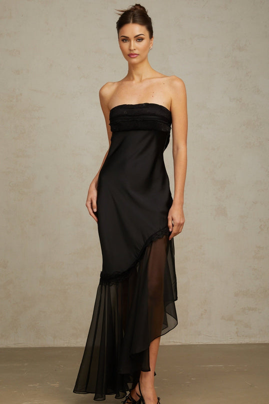 A long black satin maxi dress with sheer tulle panels featuring a fitted bodice and flowing skirt