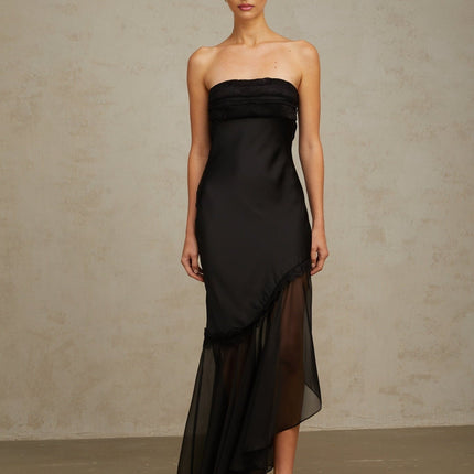 A long black satin maxi dress with sheer tulle panels featuring a fitted bodice and flowing skirt