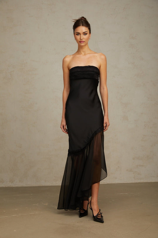 A long black satin maxi dress with sheer tulle panels featuring a fitted bodice and flowing skirt