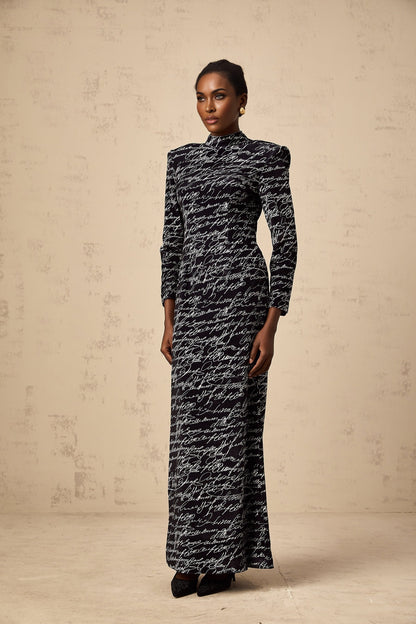 A long black velvet maxi dress with jade colored letter print design adorning the fabric