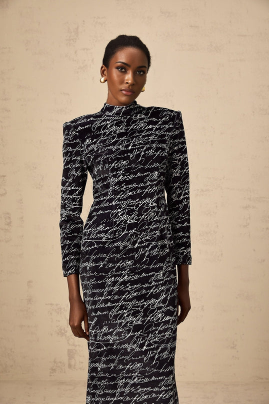 A long black velvet maxi dress with jade colored letter print design covering the fabric