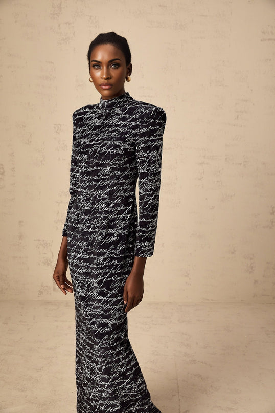 A long black velvet maxi dress with jade colored letter print design covering the fabric