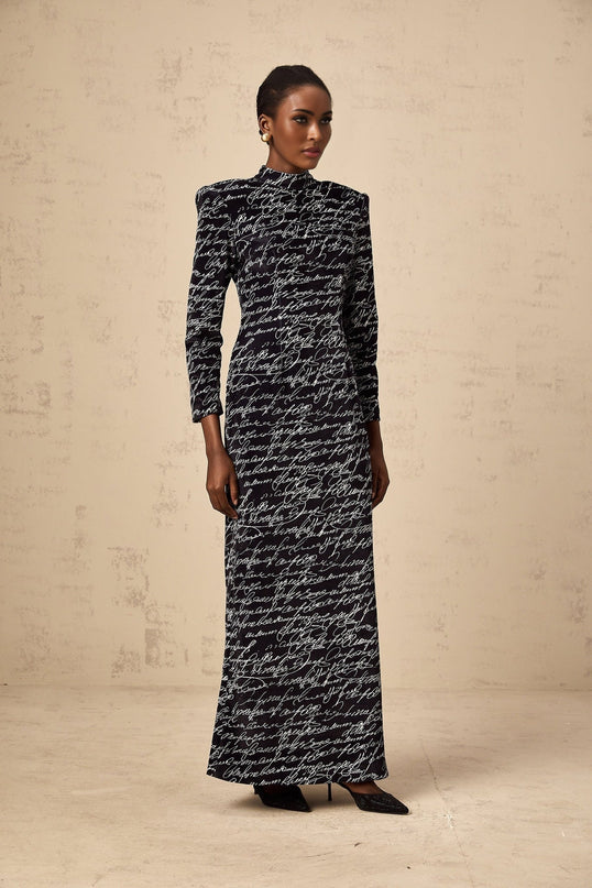 A long black velvet maxi dress with jade colored letter print pattern throughout the fabric