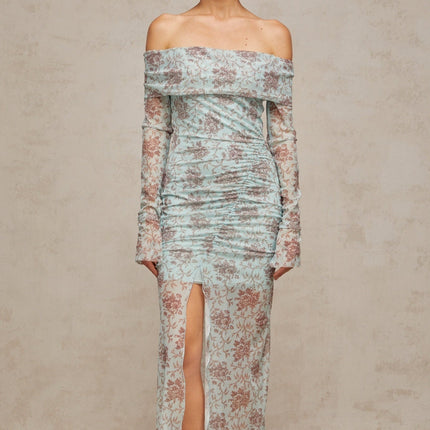 A long blue maxi dress with a floral print pattern and ruched detailing throughout the garment