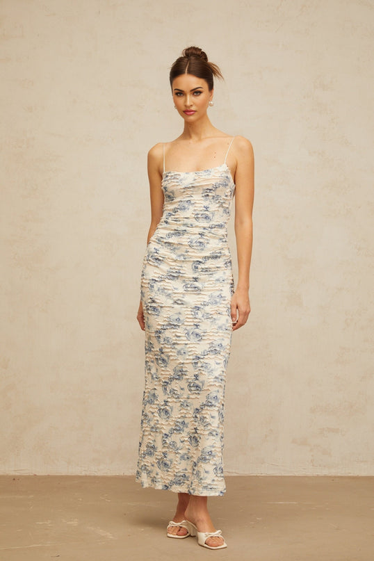 A long blue maxi dress with a textured floral print pattern covering the entire garment