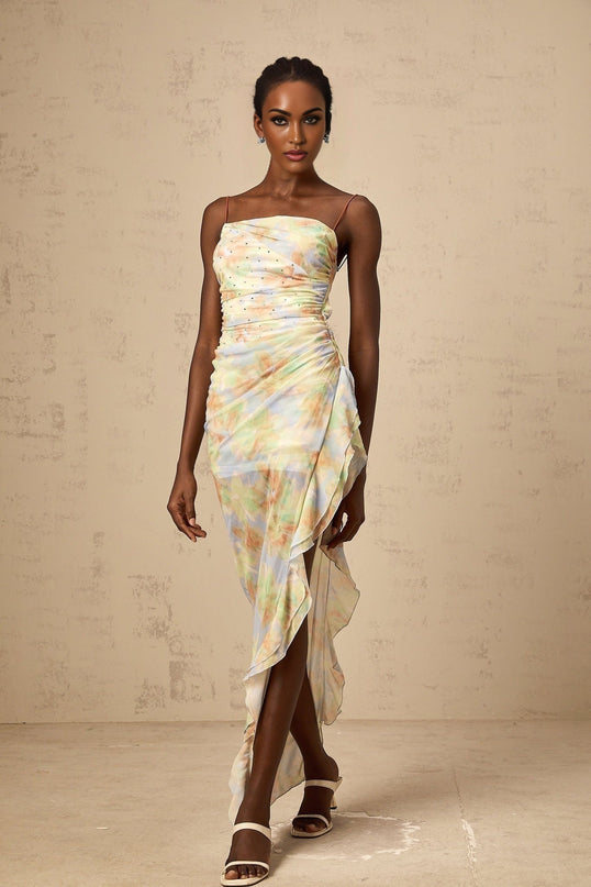 A long blue maxi dress with an asymmetric design featuring a floral print pattern and ruched details