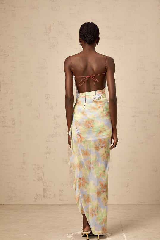 A long blue maxi dress with an asymmetric design featuring a floral print pattern and ruched details