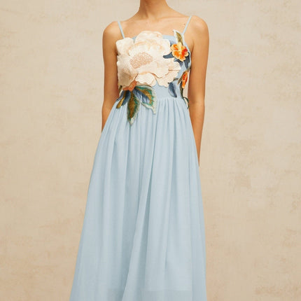 A long blue maxi dress with shirred detailing and floral embroidery covering the fabric named Josette