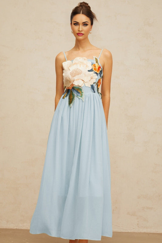 A long blue maxi dress with shirred detailing and floral embroidery covering the fabric named Josette