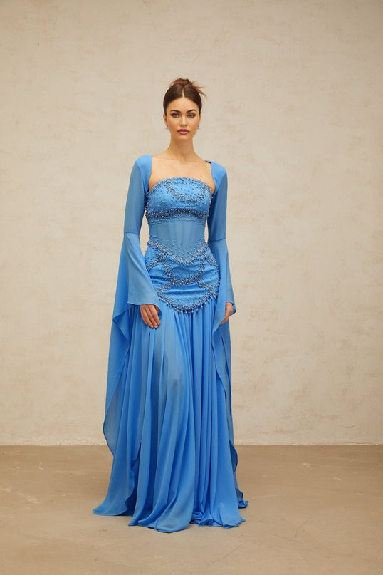 A long blue pleated maxi dress with faux pearl embellishments by Gaelle