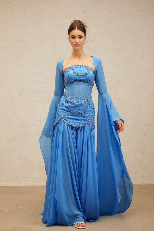 A long blue pleated maxi dress with faux pearl embellishments by Gaelle