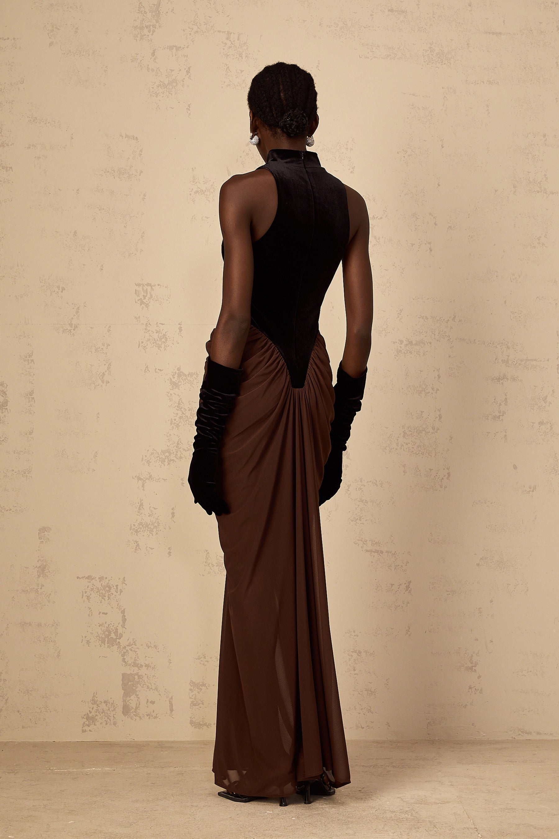 A long brown dress with velvet panels and ruched details styled as a maxi length garment named Mathilde