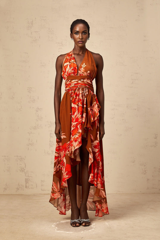 A long brown maxi dress with a floral print pattern and an asymmetrical hemline featuring a flowy design and feminine silhouette